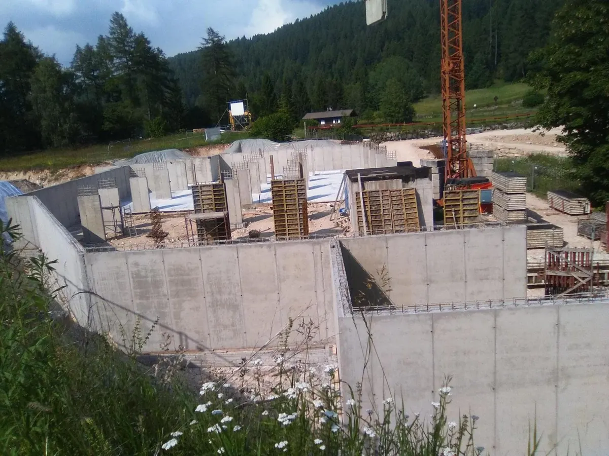 Muri di fondazione in cemento armato di una nuova costruzione, con una gru e il bosco sullo sfondo
